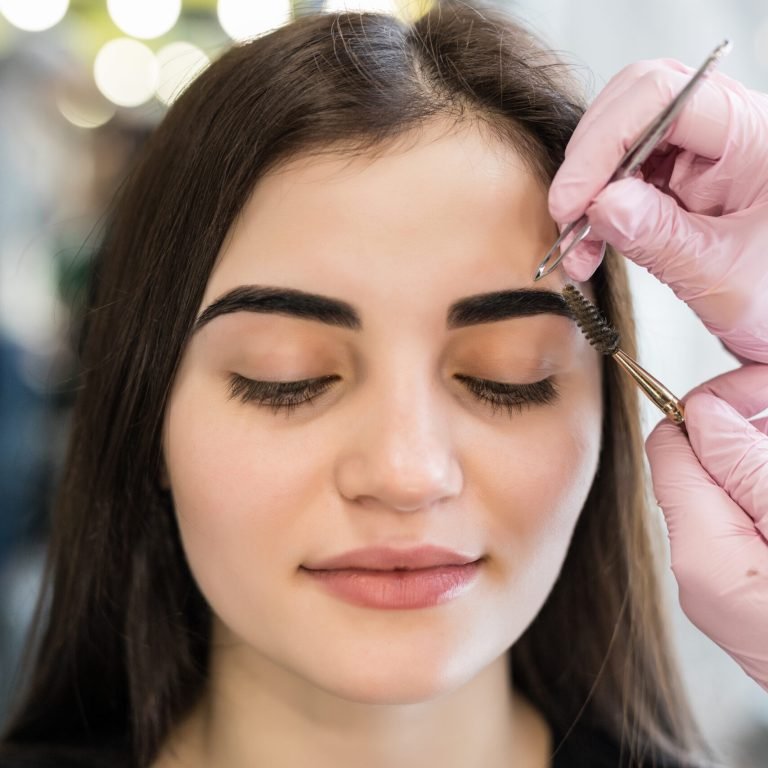 master doing final steps in make-up procedure for model with green eyes